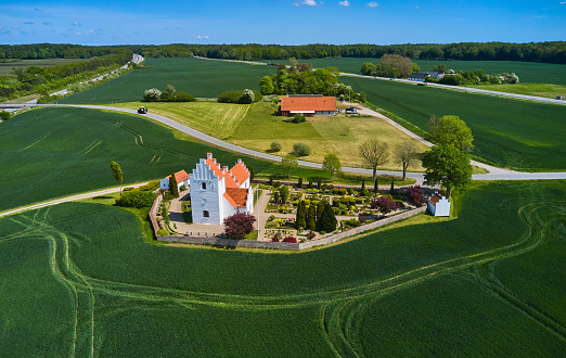 Traditional old village church surrounded by green agricultural fields. Drone point of view
