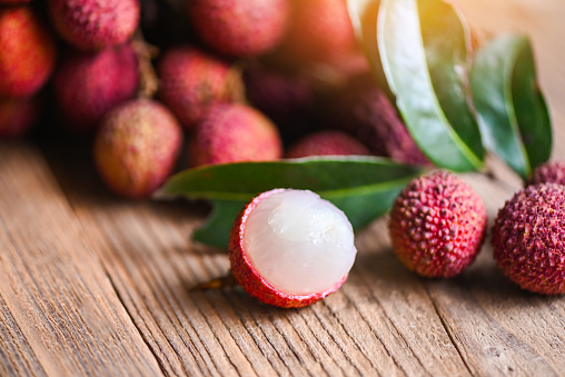 Lychee fruit and green leaf on wooden background, fresh ripe lychee peeled from lychee tree at tropical fruit Thailand in summer