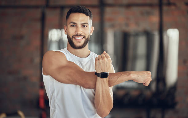 Portrait of an athlete stretching his shoulder. Young man doing an arm warmup before a workout. Bodybuilder getting ready to exercise in the gym. Confident fit man stretching his arm before a workout retrato de un atleta estirando el hombro. joven haciendo un calentamiento de brazos antes de un entrenamiento. culturista preparándose para hacer ejercicio en el gimnasio. hombre en forma y seguro estirando su brazo antes de un entrenamiento