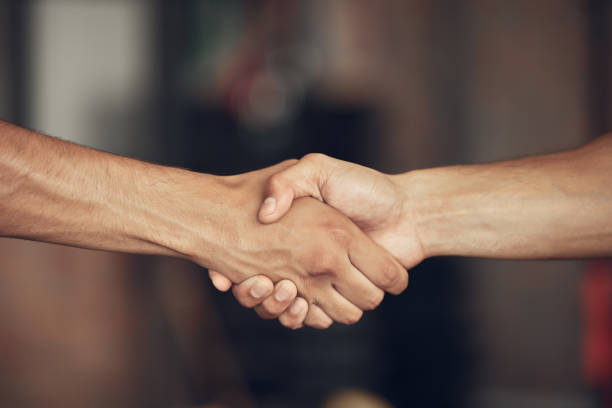 Closeup on hands of athletes handshake in the gym. Two bodybuilders greeting before workout together. hands of fit men collaborate before exercise. Athletes saying hello in the gym stock photo