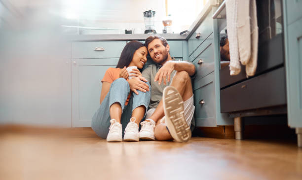 istock Young happy interracial couple bonding while drinking coffee together at home. Loving caucasian boyfriend and mixed race girlfriend sitting on the kitchen floor. Cheerful husband and wife relaxing and spending time together 1400424183