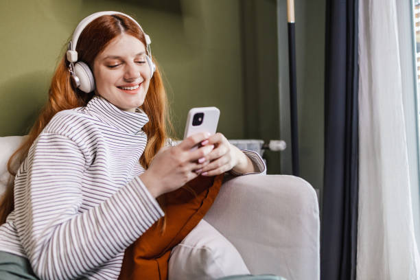 istock Woman is sitting on the sofa ang using phone 1400425155