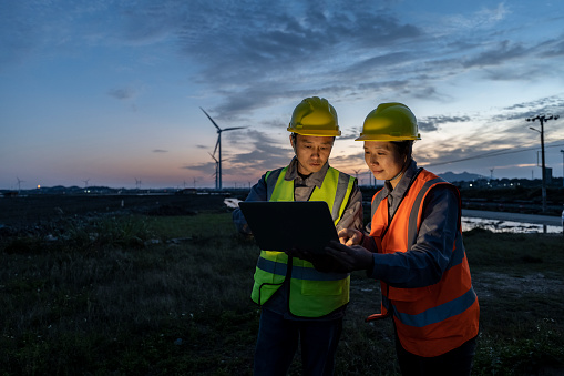 Two engineers work at a seaside wind farm
