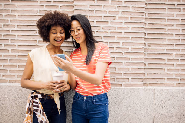 Best friends enjoying in Madrid, using smartphone and having fun