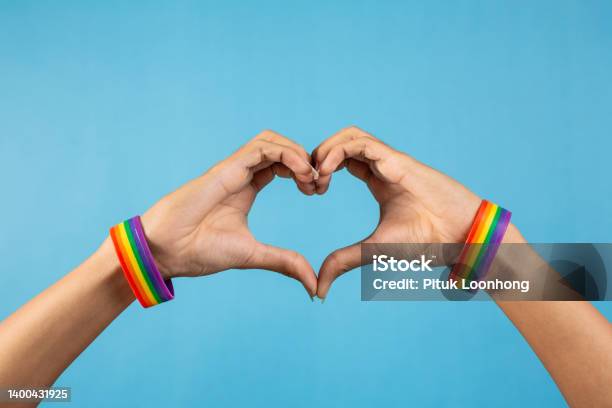 Hand Making Heart Sign With Gay Pride Lgbt And Rainbowpatterned Wristband On Wrists On Blue Color Background Lgbt And Love Concept Stock Photo - Download Image Now
