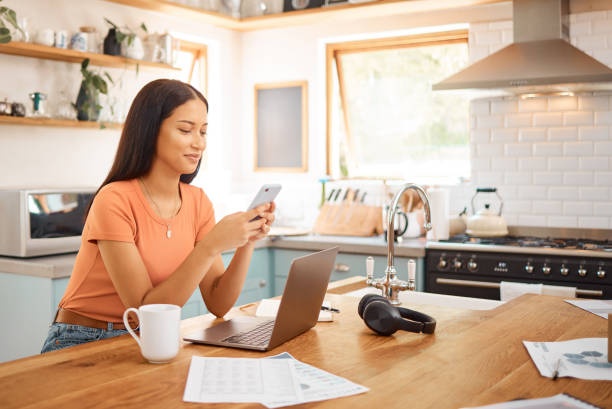 istock Young happy mixed race businesswoman using a phone while working from home. One content hispanic woman using social media on her cellphone while using a laptop 1400435770