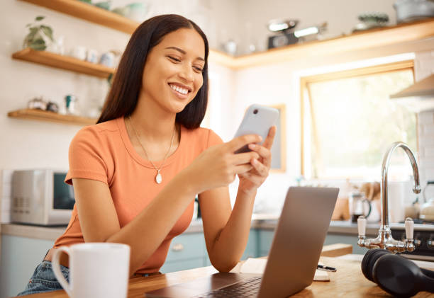 istock Young beautiful happy mixed race businesswoman using a phone while working from home. Content hispanic woman using social media on her cellphone while using a laptop 1400435774