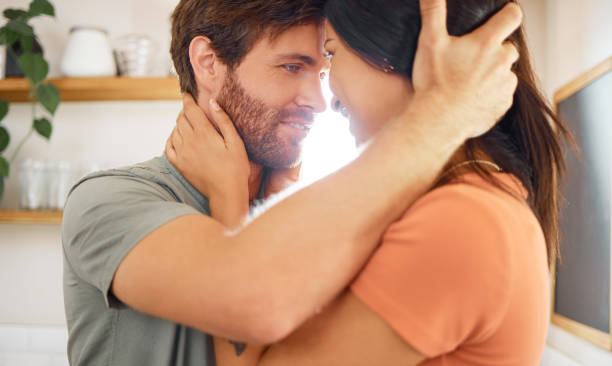 istock Young content interracial couple bonding staring into each other’s eyes at home. Loving caucasian boyfriend and mixed race girlfriend standing in the kitchen. Husband and wife relaxing and spending time together in the morning 1400435788