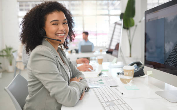 retrato de una joven agente de centro de llamadas feliz de raza mixta que responde llamadas mientras usa un auricular en el trabajo. una empresaria hispana con un afro rizado hablando en una llamada mientras usa una computadora de escritorio en un escritor - secretary fotografías e imágenes de stock