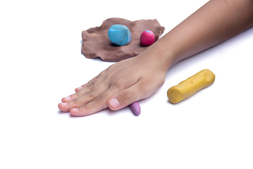 Hand of child is playing with molding plasticine isolated on white background.