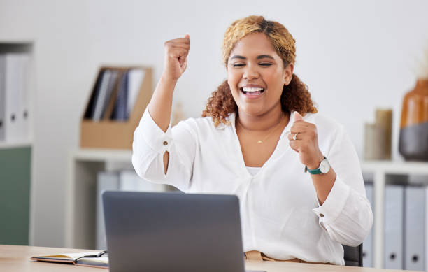 istock Mixed race businesswoman cheering in joy while using a laptop alone at work. One hispanic businesswoman looking excited while working on a computer at a desk in an office 1400436095