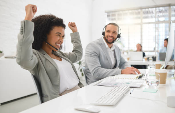 istock Young cheerful mixed race female call center agent cheering in joy while answering calls wearing a headset at work. Joyful hispanic businesswoman talking on a call while working on a desktop computer at a desk in an office 1400436492