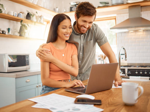 istock Young happy interracial couple bonding while working on a laptop together at home. Caucasian boyfriend and girlfriend planning and using a laptop. Content wife and husband browsing online on a computer 1400436732