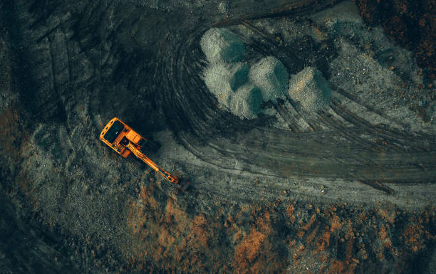 excavadora brillante en el trabajo en una vista de fondo oscuro desde un dron - minería fotografías e imágenes de stock