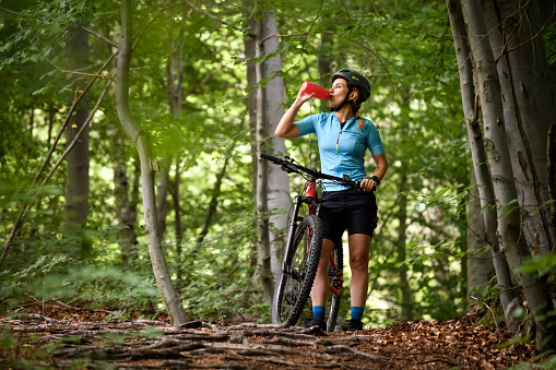 Young woman with mountain bike on Italian mountains: Drinking water
