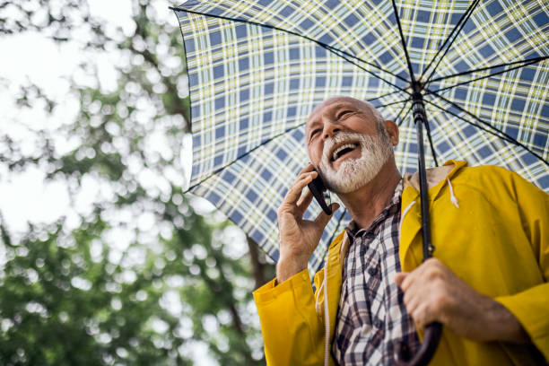 istock Senior man using phone on a rainy day walk 1400442176