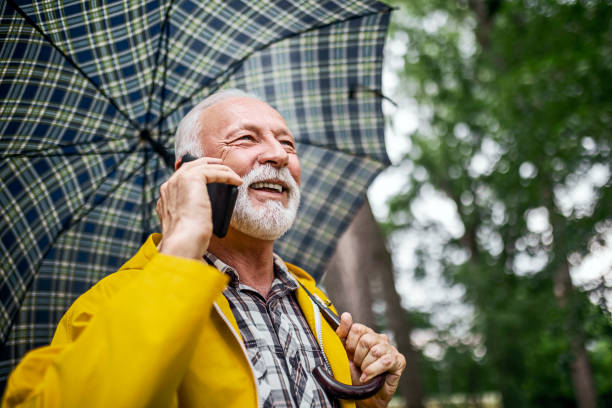 istock Senior man in woods on a raining day wearing yellow using phone 1400442194