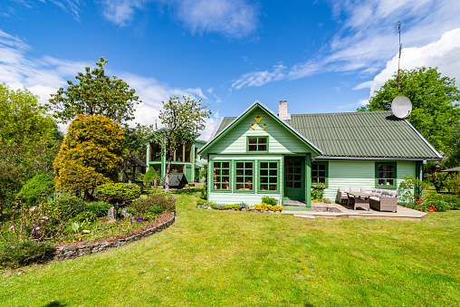 A restored old farmstead house in a countryside. Repainted to match green environment. Terrace in front of the house.