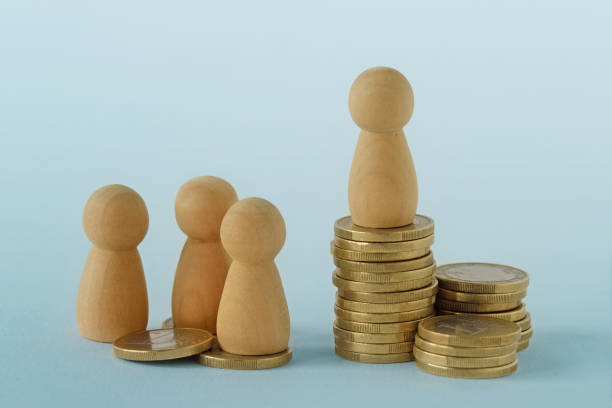 Pawns with stacks of coins - Concept of social and economic inequality stock photo