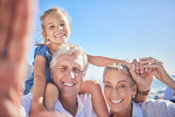 istock Loving grandparents taking a selfie while spending time with their adorable little granddaughter against a blue sky. Adorable little girl sitting on her grandfathers shoulders while her grandmother holds her hand and protects her from falling 1400443924