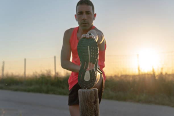 istock Young runner man doing leg stretches on a wooden pole. 1400444609