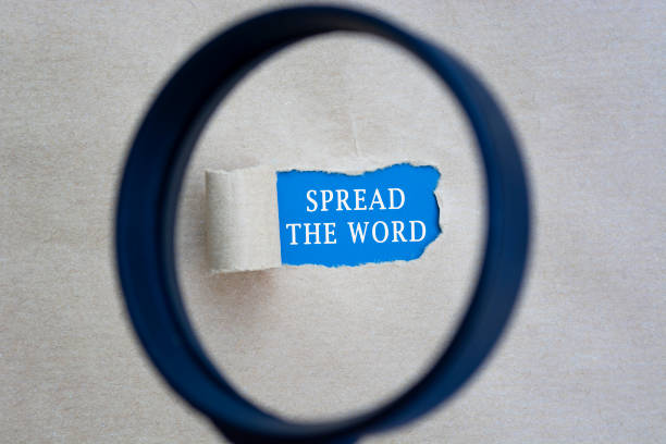 istock Spread the word text on torn paper with magnifying glass. Network concept. 1400444869