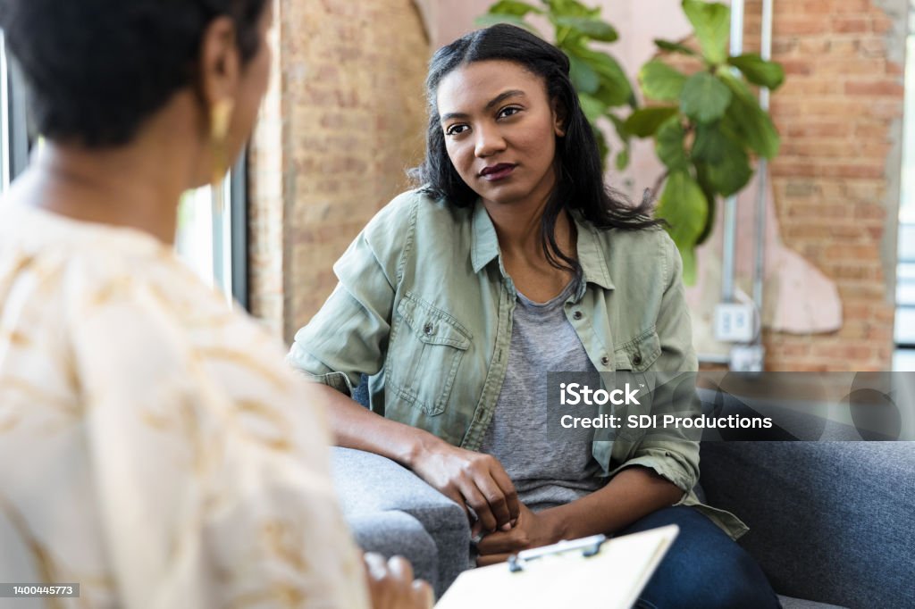 Young woman focuses on female counselor's advice The young adult woman focuses completely on the advice being given by the unrecognizable female therapist. Psychotherapy Stock Photo