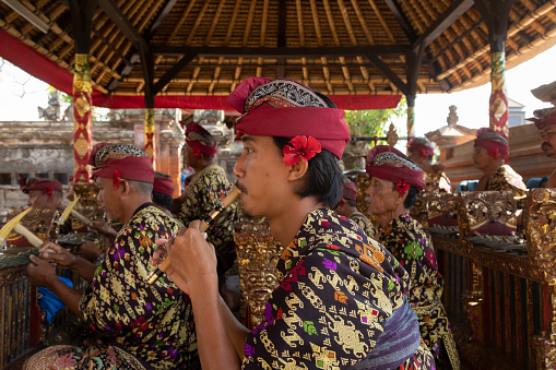 Bali, Indonesia - 28 Aug. 2019: A man plays a bamboo flute, known as a suling, as part of a musical ensemble, or gamelan, during a performance