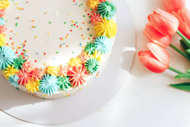 istock White cake decorated with multi-colored cream near red tulips 1400448032