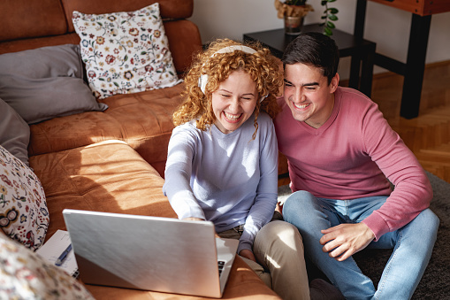 Young woman showing on the laptop to man interesting details of photos from vacation