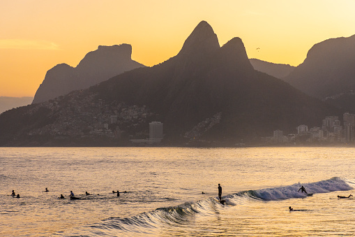 Beautiful beach sunset view with ocean, mountains and orange sky in Rio de Janeiro, State of Rio de Janeiro, Brazil