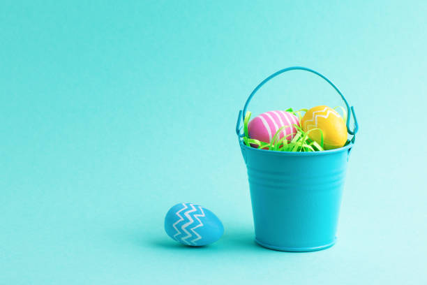 istock Spring holiday composition with colourful Easter eggs in small decorative bucket isolated on blue background. 1400457190