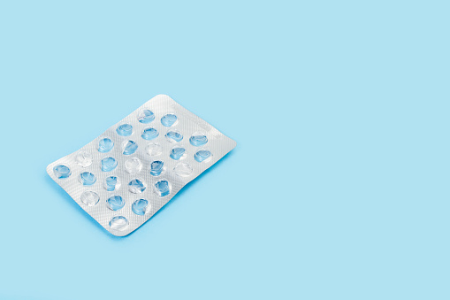 Empty medical pills blisters on a light blue background with copy space
