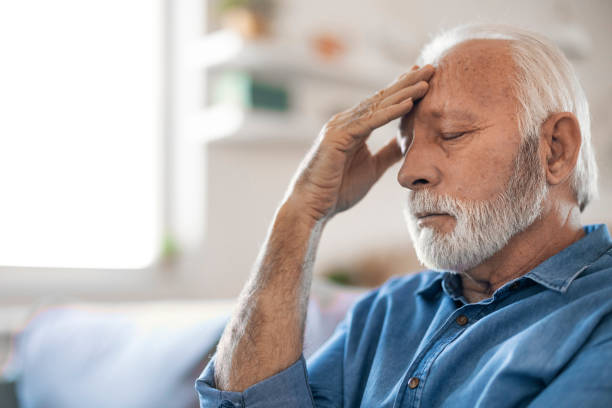 istock Unhappy Senior Man Sitting on the Sofa while Having Headache 1400459598