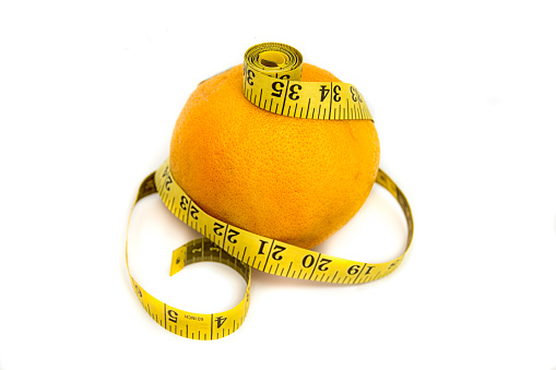 Diet concept: grapefruit and measuring tape on white background