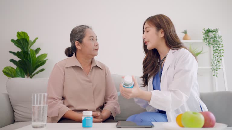 Asian nurse or doctor explaining therapy to senior woman and senior man at home.