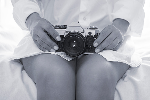 young woman holding analog camera on her lap