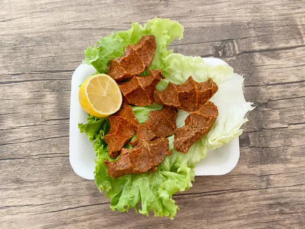 Traditional Turkish raw meatballs cig kofte in the plate on the wood table