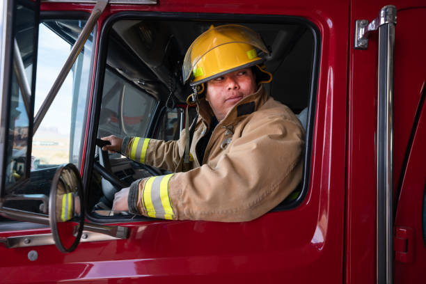 istock Young Firefighter in the Fire Station in full fire protective gear, turnout, with Fire Engine 1400469700