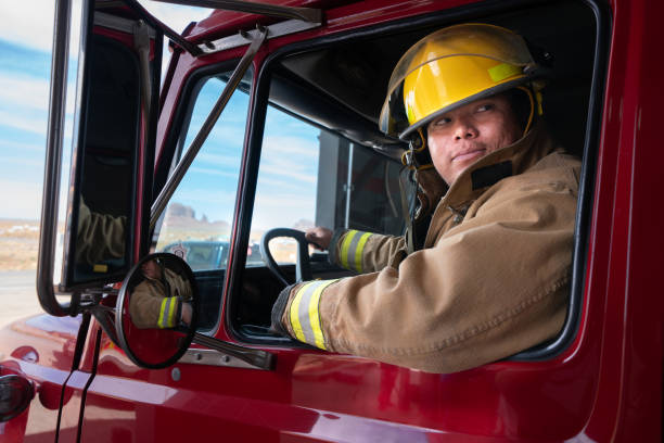 istock Young Firefighter in the Fire Station in full fire protective gear, turnout, with Fire Engine 1400469780