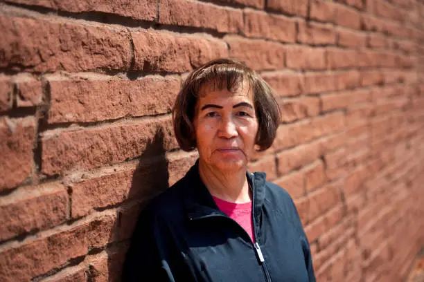 Middle Aged Indigenous Navajo Woman Portrait with Shallow Depth of Field on a Brick Wall in Monument Valley Utah on a Sunny Day
