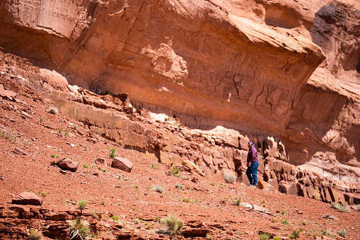 Middle Aged Indigenous Navajo Man Hiking and Walking Alone in the Sandstone Red Rock Desert and Cliffs of Monument Valley Utah