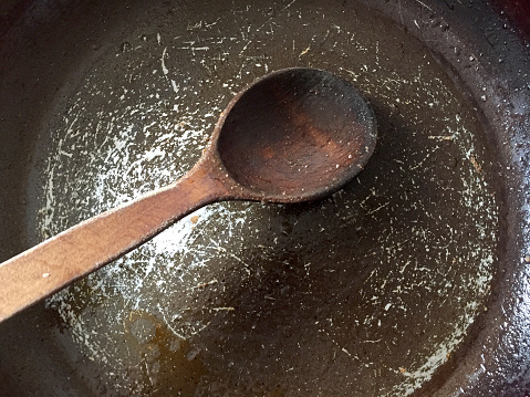 Directly above empty and dirty cooking pan with wooden spoon