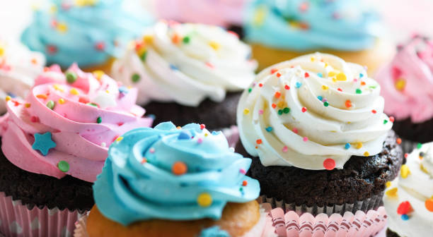 ピンクの白と青のクリームとカラフルなふりかけのカップケーキがクローズアップされています。