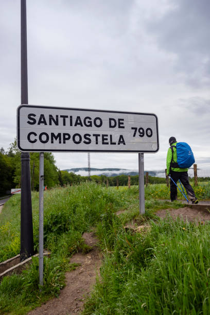 A man walks on the Camino de Santiago in Roncesvalles, Spain, passing a road sign giving the distance to Santiago de Compostela as 790 kilometers, on May 29, 2018.