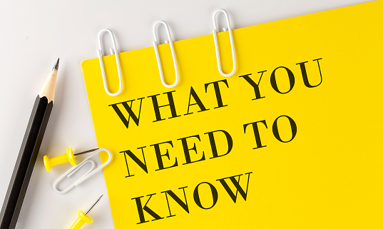 WHAT YOU NEED TO NOW word on yellow paper with office tools on white background
