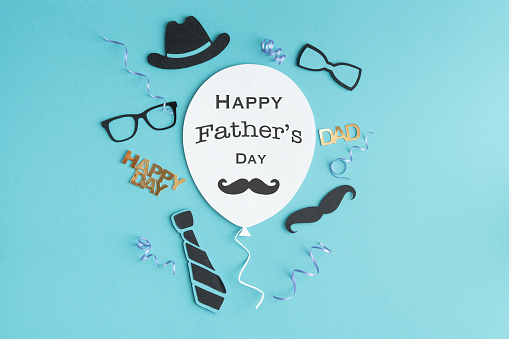 Father's Day greeting balloon card with symbols decoration on paper on blue background. Copy space.