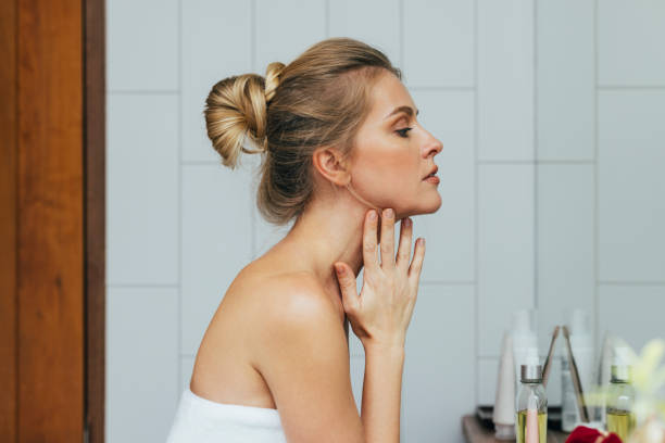 woman looking herself in the bathroom mirror - maquiagem ceremonial imagens e fotografias de stock