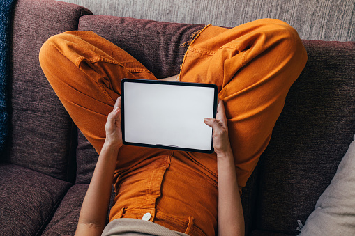 Above shot of an anonymous woman holding a tablet device in her lap.