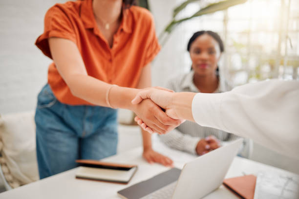 closeup of hispanic businesswoman shaking hands with colleague during a meeting in an office. motivated woman finalising a successful promotion, deal and merger. coworkers greeting while collaborating in a creative startup agency - onboarding imagens e fotografias de stock